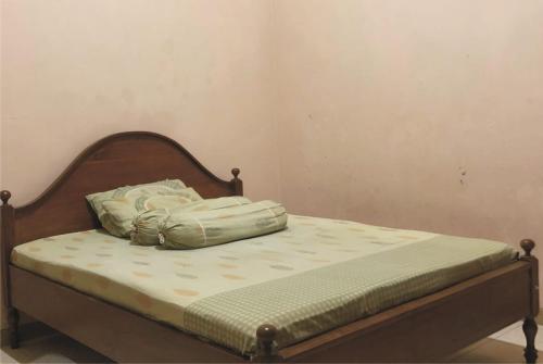 a bed with a wooden headboard with a pillow on it at Griya Erlangga in Kediri