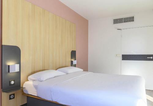 a bedroom with a white bed and a tv at B&B HOTEL Nîmes Centre Arènes in Nîmes