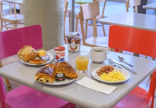 a table with two plates of breakfast foods and orange juice at B&B HOTEL Nîmes Centre Arènes in Nîmes