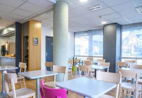 a restaurant with tables and chairs and windows at B&B HOTEL Nîmes Centre Arènes in Nîmes