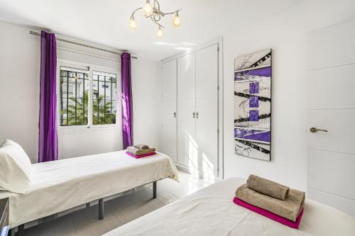 two beds in a room with purple curtains at Casa Stefania in Marbella