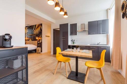 a kitchen with a table and two yellow chairs at L'essentiel in Le Creusot