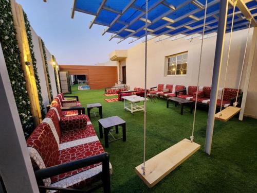 a patio with red chairs and swings in a building at استراحة وشاليه وقاعة السلطانه in Al-Salam