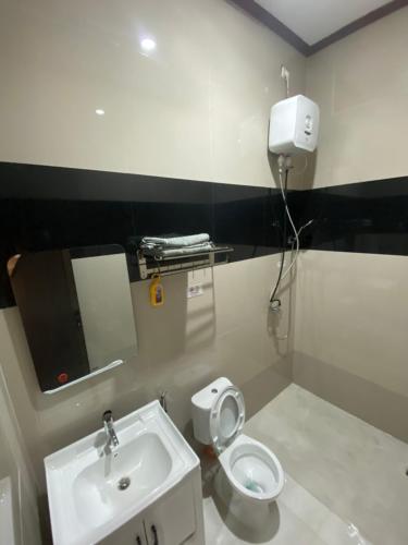 ein Badezimmer mit einer weißen Toilette und einem Waschbecken in der Unterkunft EMWEKA Residence Balikpapan in Balikpapan