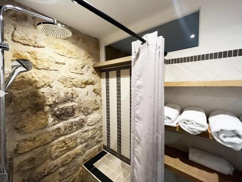 y baño con ducha y pared de piedra. en Urban Flat 43 - Charming Parisian Flat near Grands Boulevards, en París