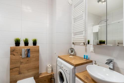 ein Badezimmer mit einer Waschmaschine und einem Waschbecken in der Unterkunft Prokocim Blue Studio in Krakau