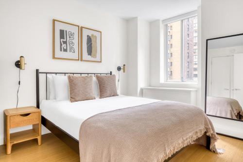 a white bedroom with a bed and a window at Midtown E 2br w elevator doorman gym nr UN NYC-752 in New York