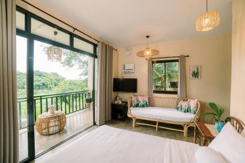 a living room with a couch and a balcony at Samkara Restaurant and Garden Resort in Majayjay