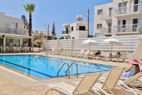 a swimming pool with people sitting in lawn chairs next to a hotel at Napa City Apartments in Ayia Napa