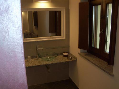 uma casa de banho com um lavatório de vidro e um espelho. em Poggio d'Incanto em Bettola