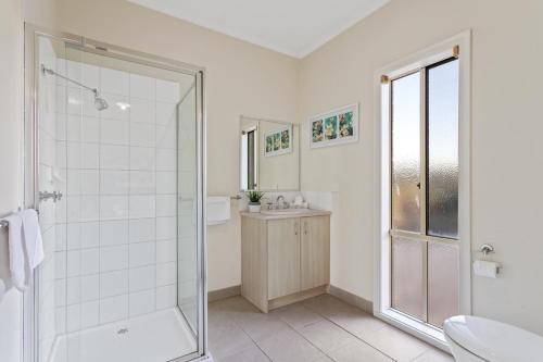 uma casa de banho branca com um chuveiro e um lavatório. em Loemans Lodge, 5 Bedrooms near Airport, Free Parking em Bulla