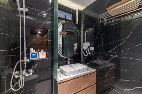 a black bathroom with a sink and a shower at SaziHome Train Street Hanoi in Hanoi