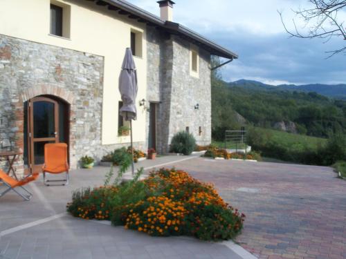 a building with a chair and an umbrella and flowers at Poggio d'Incanto in Bettola