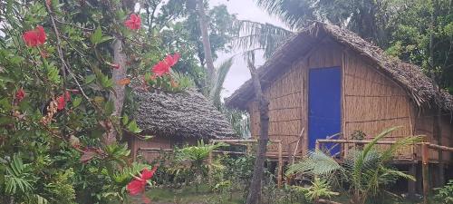 una pequeña casa con una puerta azul y árboles en Tanna Chez Nous Bungalow and Tours, en Loméméti