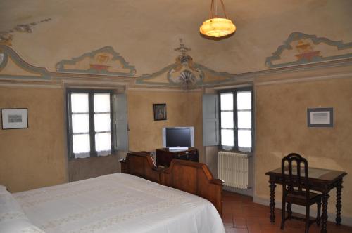 a bedroom with a bed and a tv and windows at Palazzo Tornielli in Mombello Monferrato