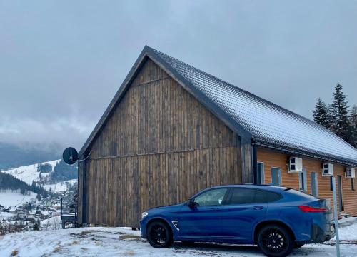 a blue car parked in front of a wooden building at Apartamenty Widokowe Na Szczycie in Korbielów
