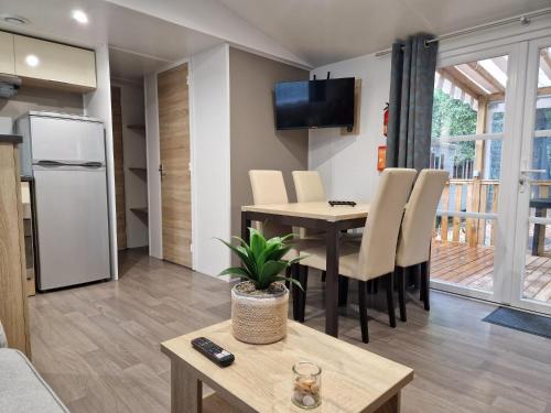 uma cozinha e sala de estar com uma mesa e um frigorífico em Mobile Home For You les Pierres Couchées em Saint-Brevin-les-Pins