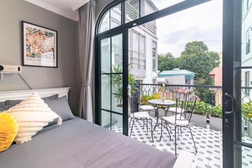 a bedroom with a bed and a balcony with a table at SaziHome Train Street Hanoi in Hanoi