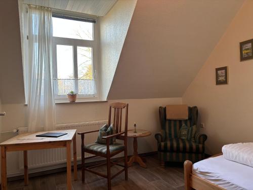 a bedroom with a bed and a table and two chairs at Heitmann`s Gasthof in Kirchlinteln