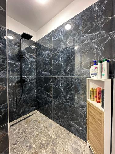 Łazienka z prysznicem wyłożona jest czarnym marmurem. w obiekcie Paradise rooftop 2 w mieście Golem