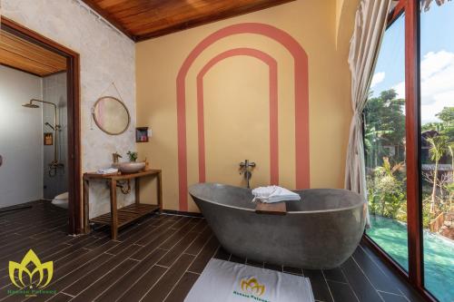 ein Bad mit einer großen Badewanne und einem Fenster in der Unterkunft Hanasa Pu Luong Resort in Pu Luong