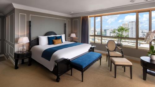 a hotel room with a bed and a desk and window at Sofitel Saigon Plaza in Ho Chi Minh City