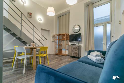 - un salon avec un canapé bleu et une table avec des chaises dans l'établissement MBA Splendide Appart - Tracy 1 - Proche du Musée du Louvre, à Paris