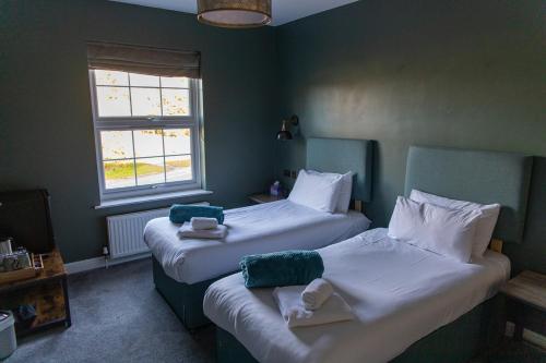 two beds in a small room with green walls at The Plough Inn in Marsham