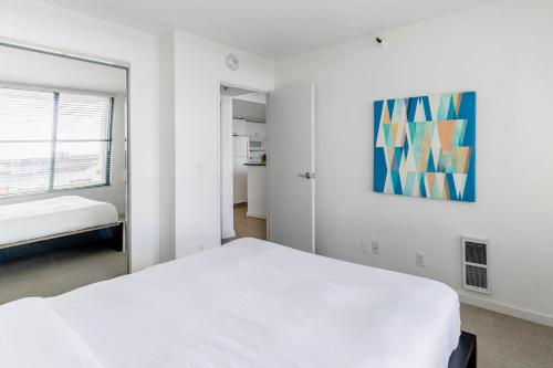 a bedroom with a white bed and a painting on the wall at South Beach 1br w sun deck gym nr waterfront SFO-1658 in San Francisco