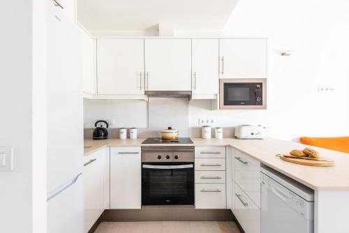 a white kitchen with white cabinets and a stove at Dos Geckos - Son Parc in Son Parc
