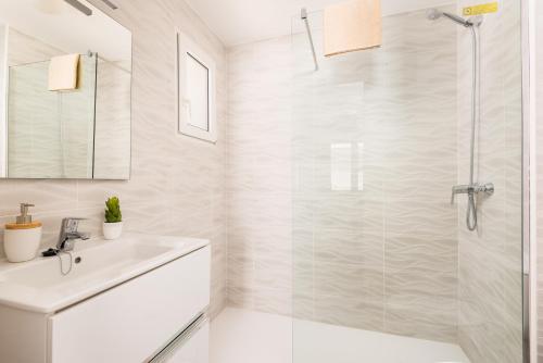 La salle de bains blanche est pourvue d'une douche et d'un lavabo. dans l'établissement Dos Geckos - Son Parc, à Son Parc