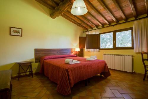 a bedroom with a red bed with two towels on it at Agriturismo Monacianello - Fontebelvedere wine estate in Ponte A Bozzone