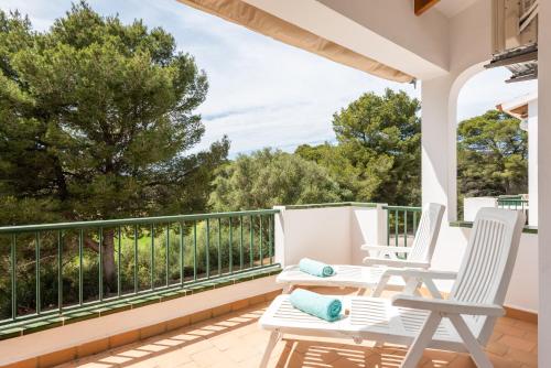 a porch with white chairs and a balcony with trees at Dos Geckos - Son Parc in Son Parc