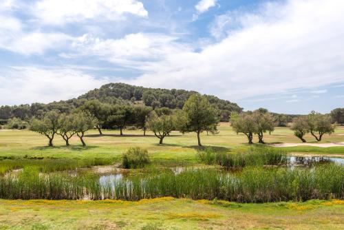 a golf course with trees and a mountain in the background at Dos Geckos - Son Parc in Son Parc