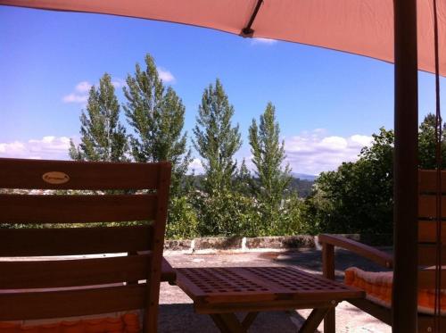 a wooden bench sitting under an umbrella on a patio at Eira das Carvalhas in Penafiel