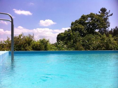 uma piscina de água azul com árvores ao fundo em Eira das Carvalhas em Penafiel