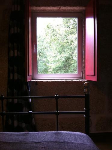 a window in a room with a bed in front of it at Eira das Carvalhas in Penafiel