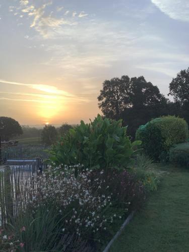 a garden with flowers and a sunset in the background at La Lézardière in Pleugriffet