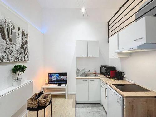une cuisine avec des placards blancs et une télévision. dans l'établissement Cosy appartement, Villeurbanne Frappaz, à Villeurbanne