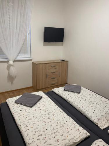 two beds in a room with a tv on the wall at Hostel u Arény in Ostrava