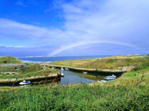 Un río con barcos en él con un arco iris en el cielo en The Waterford Arms, en Hartley