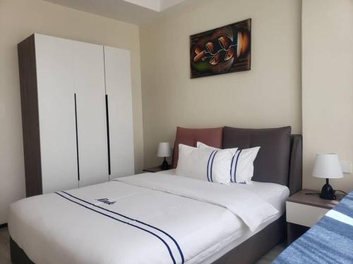 ein Schlafzimmer mit einem großen Bett mit weißer Bettwäsche in der Unterkunft GolfHill Apartment in Kigali