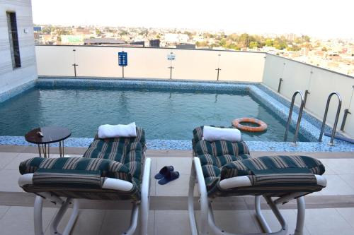 two chairs and a swimming pool on a roof at Best Western Plus Multan in Multan