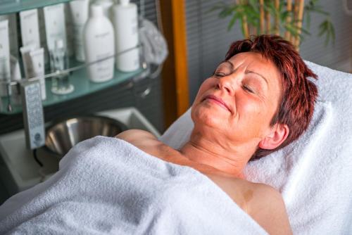 a woman laying in a hospital bed under a towel at Hotel an der Therme Bad Sulza in Bad Sulza