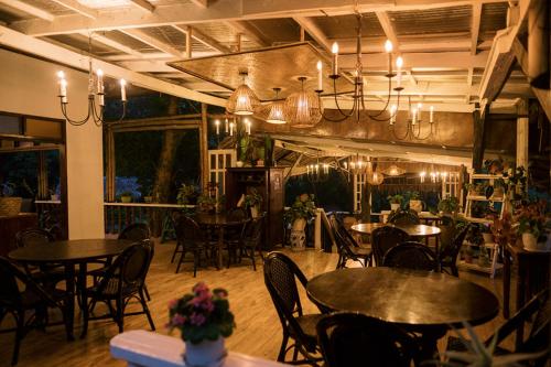 a dining room with tables and chairs and chandeliers at Samkara Restaurant and Garden Resort in Majayjay