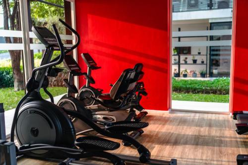 eine Reihe von Heimtrainern, die neben einer roten Wand geparkt sind in der Unterkunft The Idle Hotel and Residence in Pathum Thani