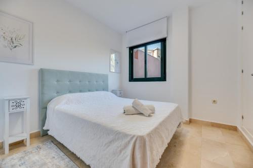 Un dormitorio blanco con una cama con una toalla. en Cabopino, cerca de todo, en Marbella