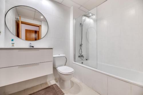 Un baño blanco con inodoro y espejo. en Cabopino, cerca de todo, en Marbella