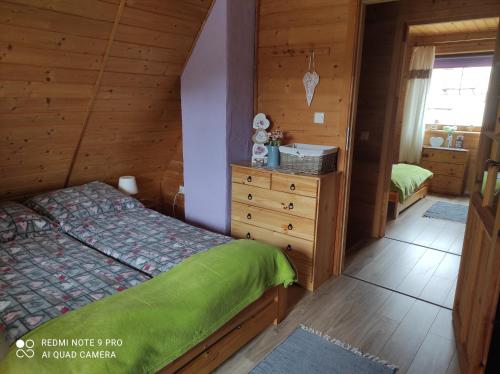 a bedroom with a bed and a dresser at Domek Mateo in Wambierzyce