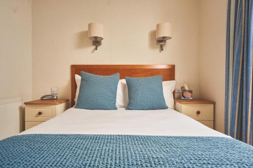 a bedroom with a bed with blue pillows at Great Western in Newquay